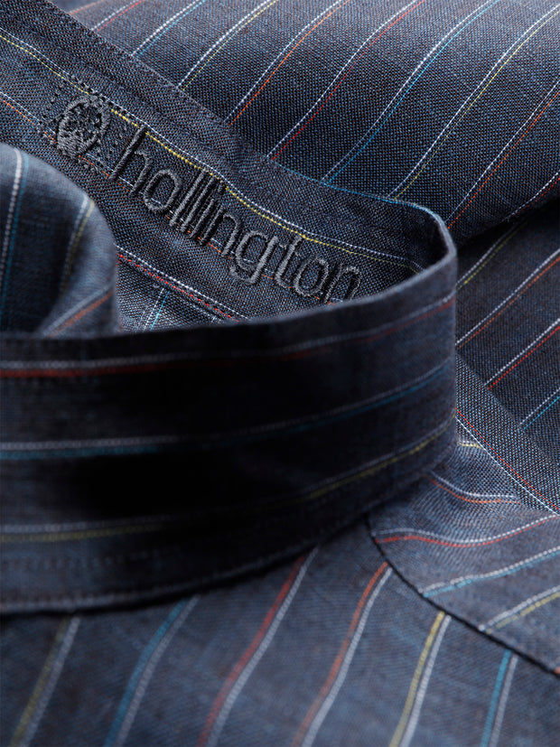 cette chemise est éditée dans une toile pur lin rayée. Elle doit son effet de faux-uni gris bleuté à la méthode de teinture "en pièce" employée. Il s’agit d’une technique prévoyant qu’un vêtement, en général en tissu brut non-coloré, soit teint à la toute fin du processus de confection, puis lavé. Cela permet d’accentuer les caractéristiques matérielles du tissu et d'obtenir cet effet irrégulier et un peu "blanchi".