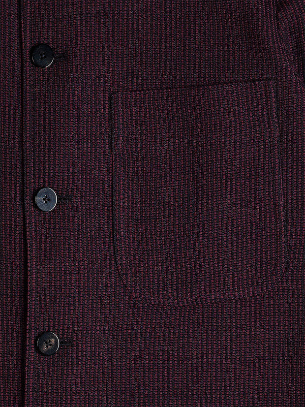 Cette veste Savoie ajutée est éditée dans un jersey à côte effet grain-de-riz. Le jersey est une maille fine tricotée originellement à partir de laine, comme celui-ci. Le résultat, très légèrement ajouré, est un poids de mi saison qui permet des effets de matière intéressants. Ici, un motif grain-de-riz en relief qui ressemble à la côte d’un velours horizontal. Sa couleur « pinot noir » se détache sur un fond noir. Un tissu de choix pour les amateurs de noir qui souhaitent se diversifier !